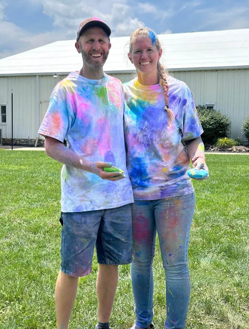 Nick and Christine at a color run event, covered in colorful powder and smiling